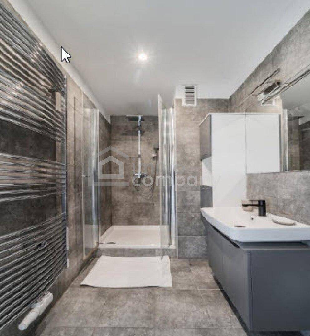 Modernes Badezimmer mit grauen Fliesen, ebenerdiger Dusche, Einzelwaschbecken und Handtuchheizkörper.