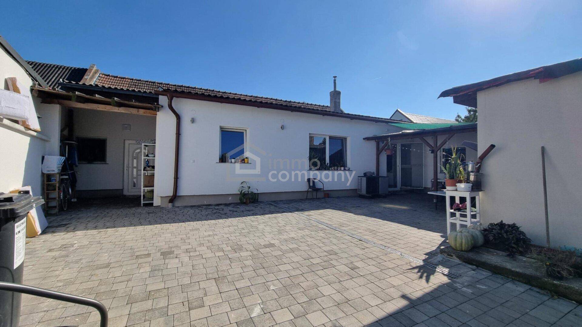 Rückseite des Hauses mit gepflastertem Hof und Zugang zu den Innenräumen.