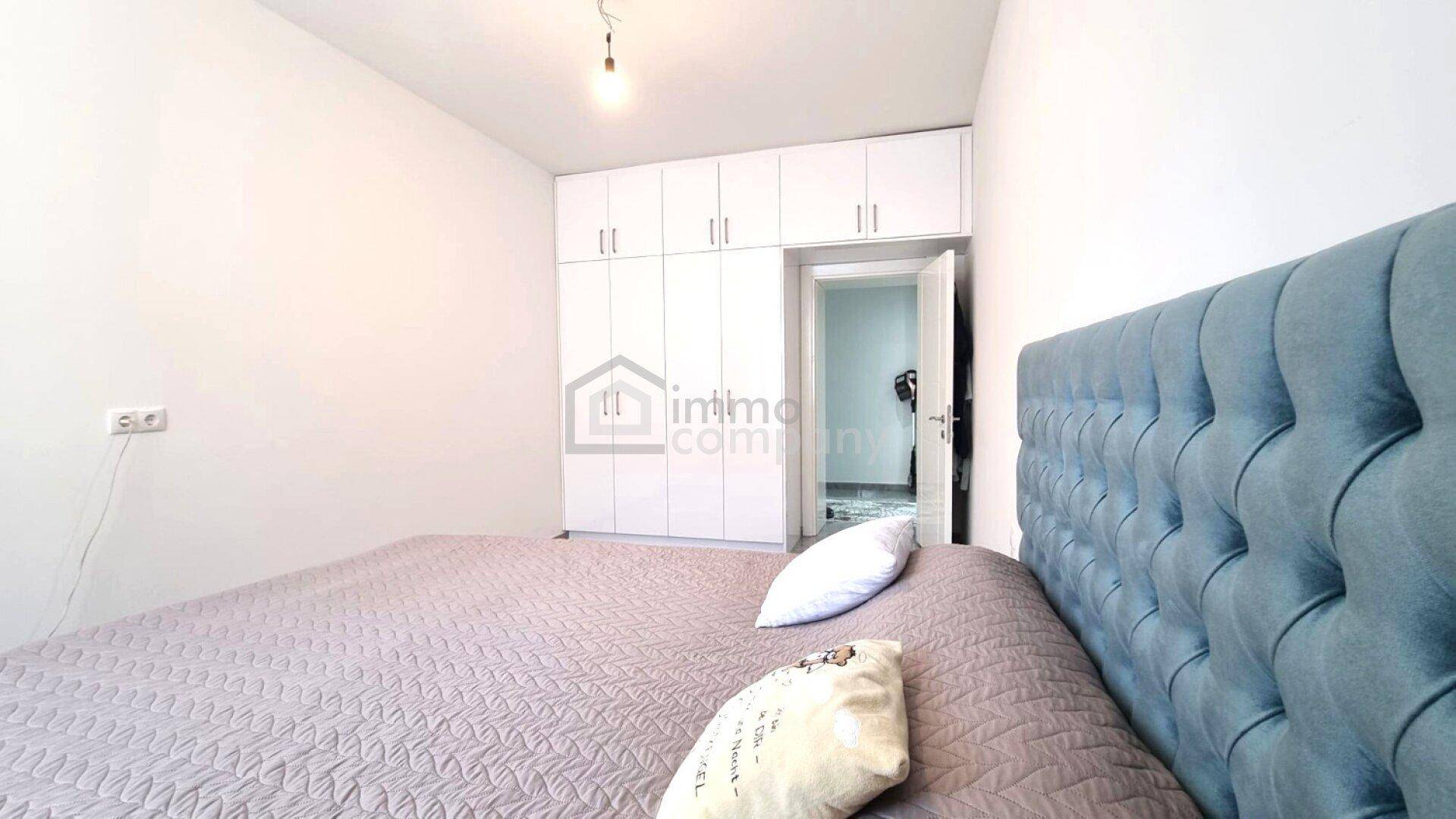 Gemütliches Schlafzimmer mit großem Bett, blauem Kopfteil und weißen Einbauschränken.