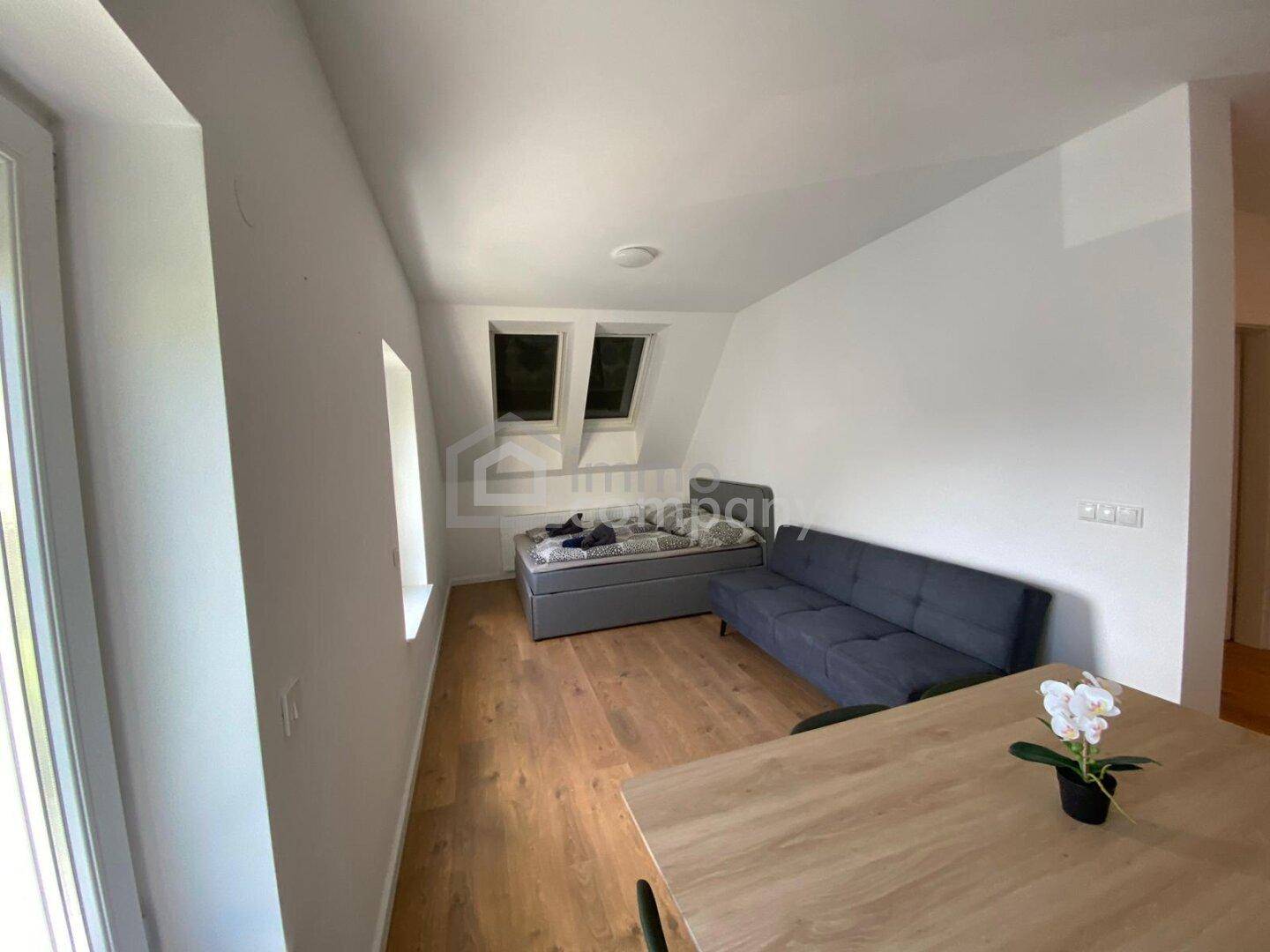 Gemütliches Schlafzimmer mit Holzboden, Dachfenstern und einem Sofa im Dachgeschoss.