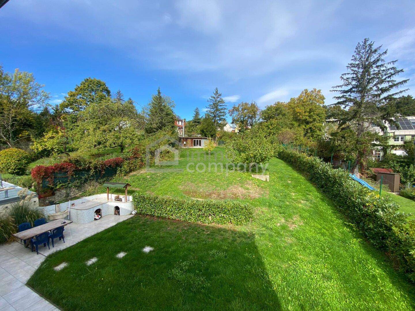 Weitläufiger Garten mit Grillplatz, Rasenflächen, altem Baumbestand und Spielgeräten.