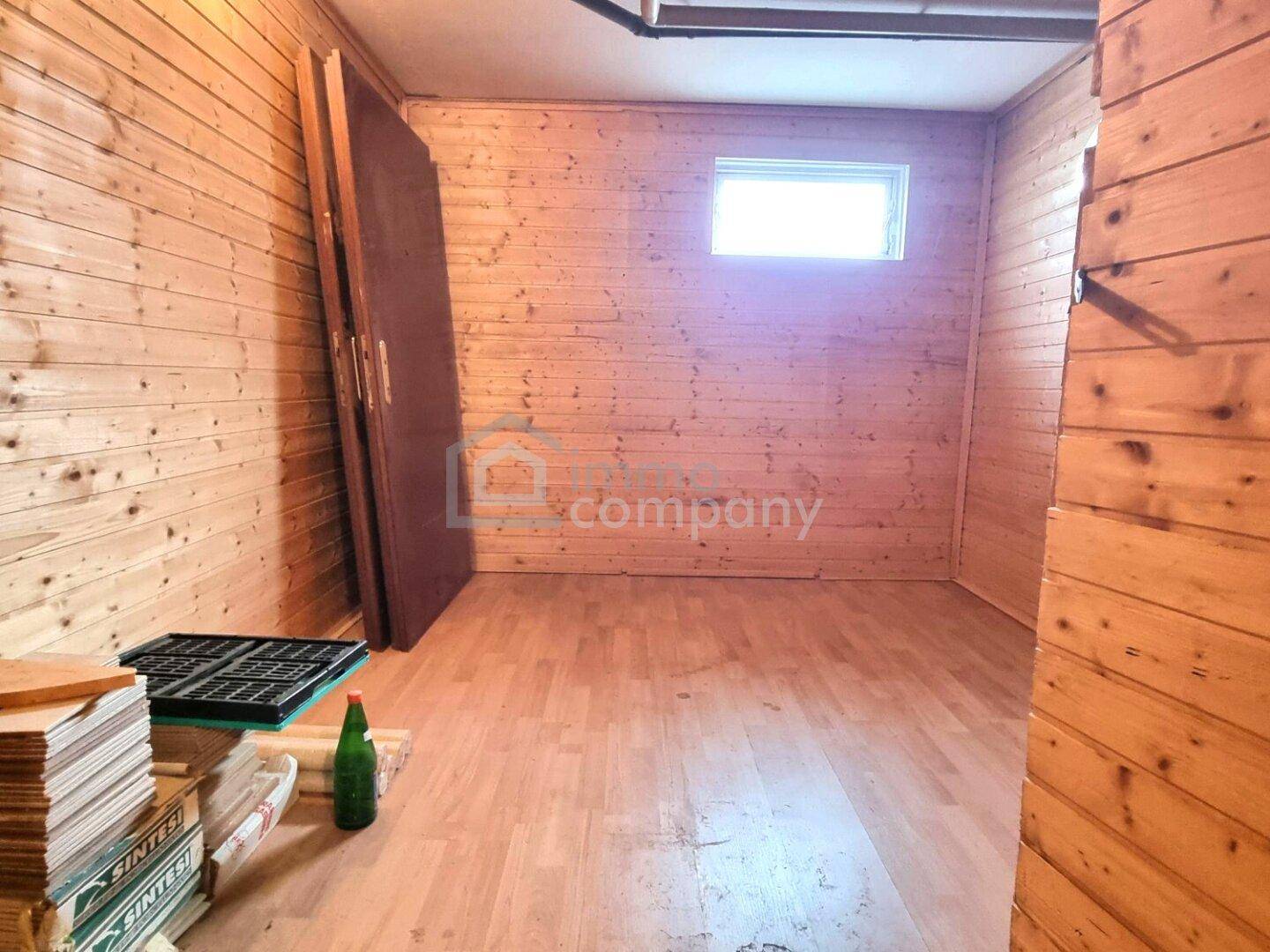 Rustikaler Raum mit Holzvertäfelung an den Wänden und Laminatboden, ideal als Abstell- oder Hobbyraum im Keller.