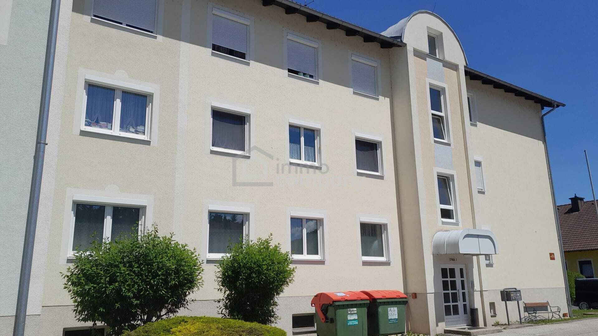 Mehrstöckiges Wohngebäude mit heller Fassade, vielen Fenstern und einem überdachten Eingangsbereich.