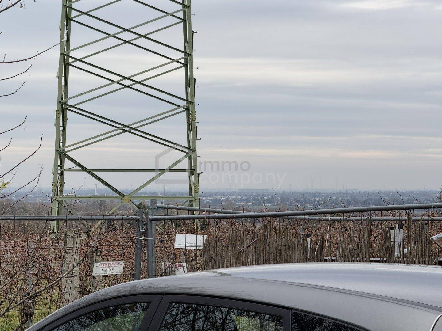 Blick auf eine Stromleitung und die entfernte Stadtlandschaft unter einem bewölkten Himmel.