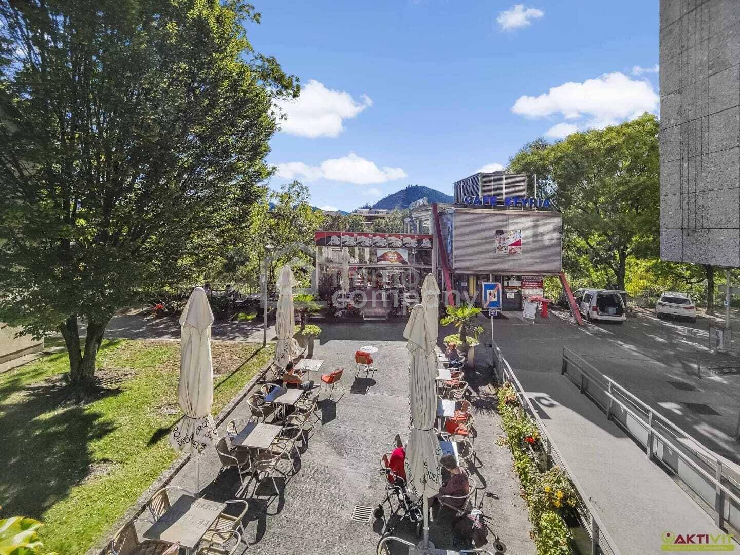 Vogelperspektive auf das Café mit großer Außenterrasse, Sonnenschirmen und angrenzendem Parkplatz.