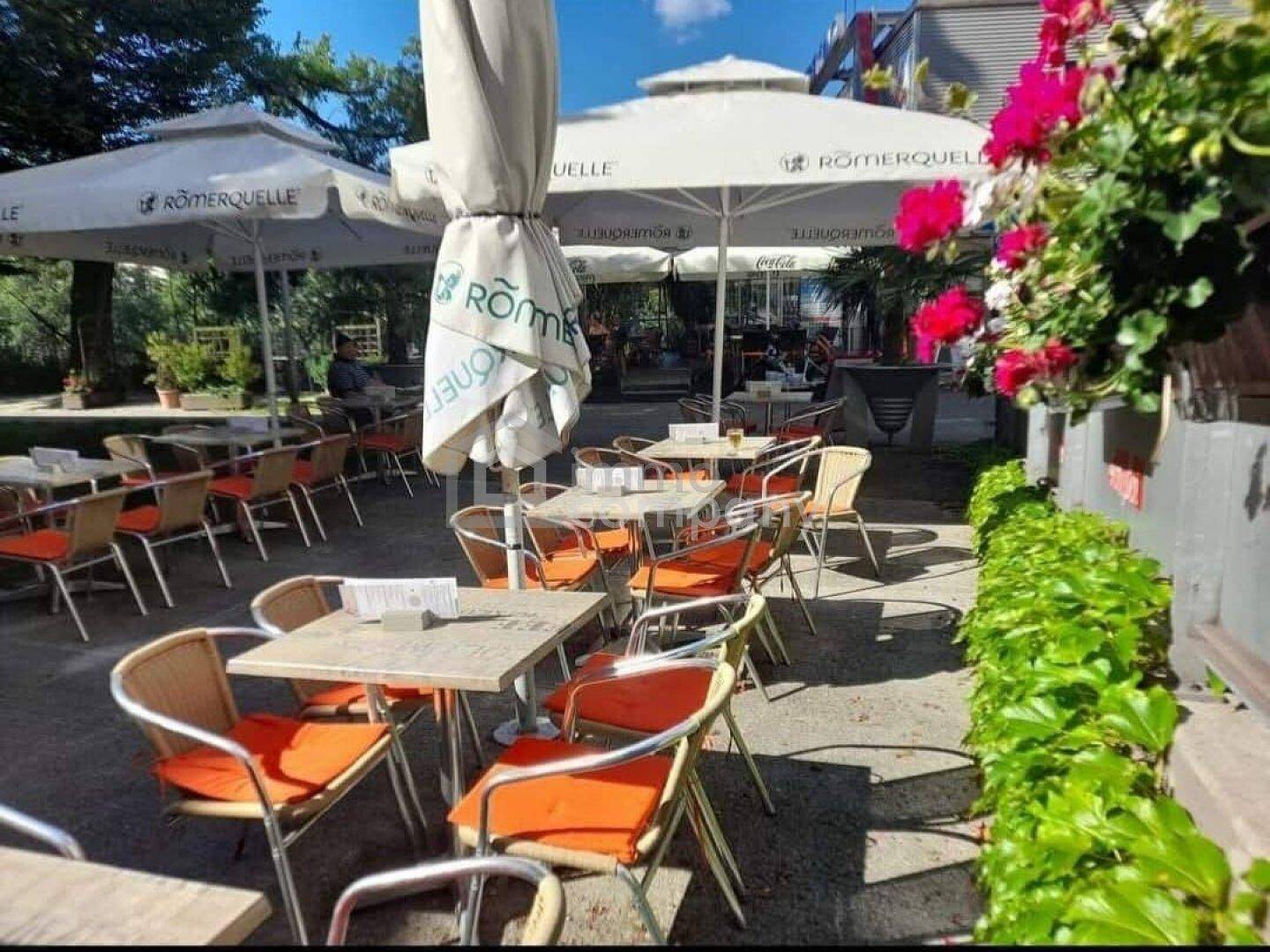 Gemütliche Außenterrasse mit Sonnenschirmen, Blumenkästen und bequemen Sitzgelegenheiten im Freien.