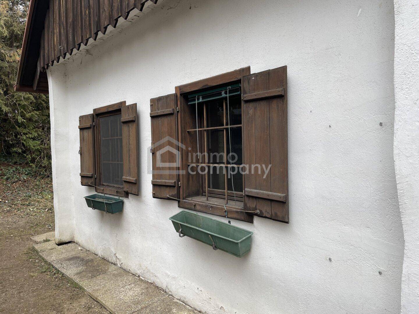 Detailansicht der Hausfassade mit traditionellen Holzfensterläden und Blumenkästen.