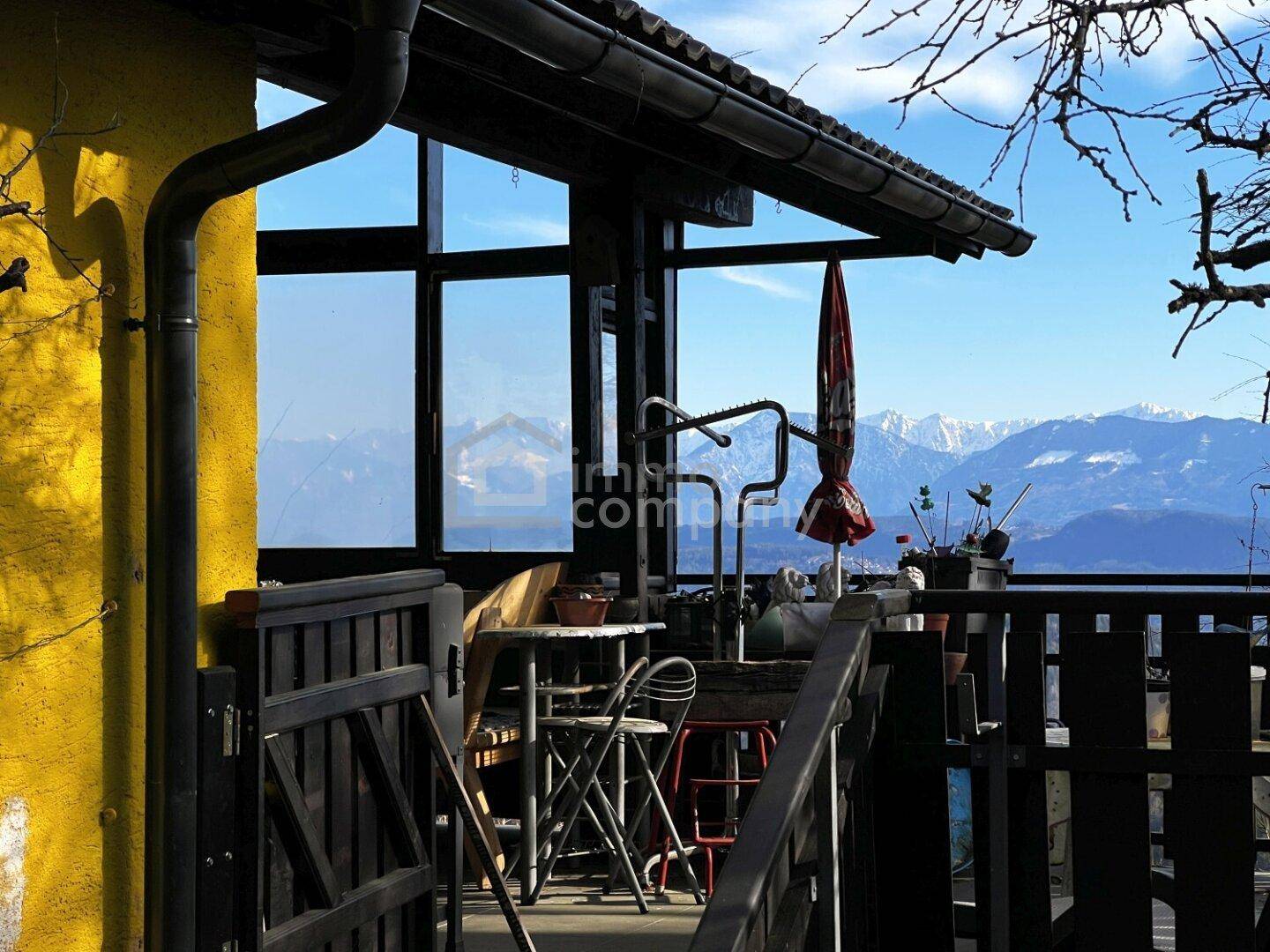 Überdachter Balkon mit Sitzgelegenheiten und weitem Bergblick.