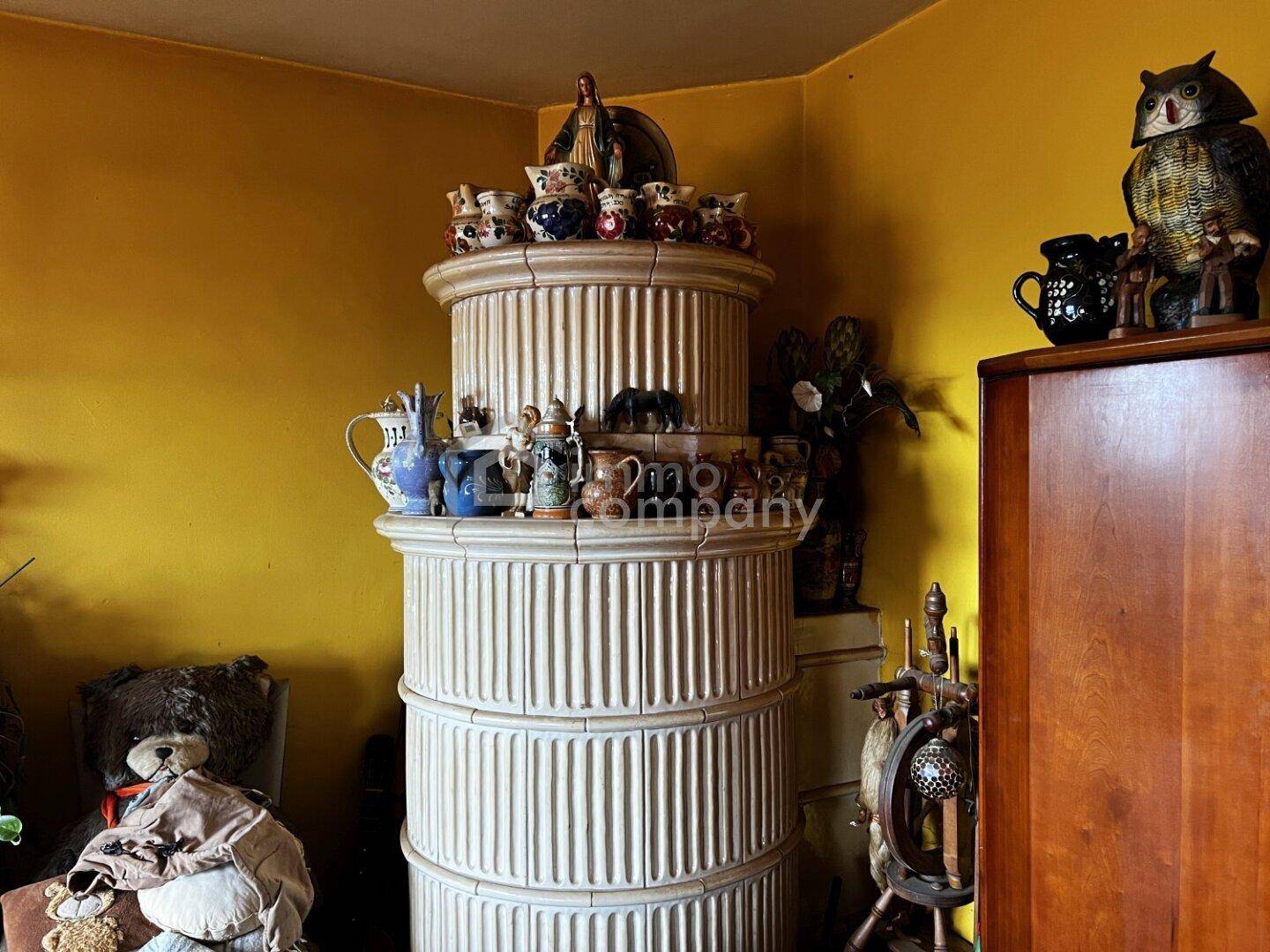 Traditioneller Kachelofen als Blickfang in einem gemütlichen Raum mit gelben Wänden.