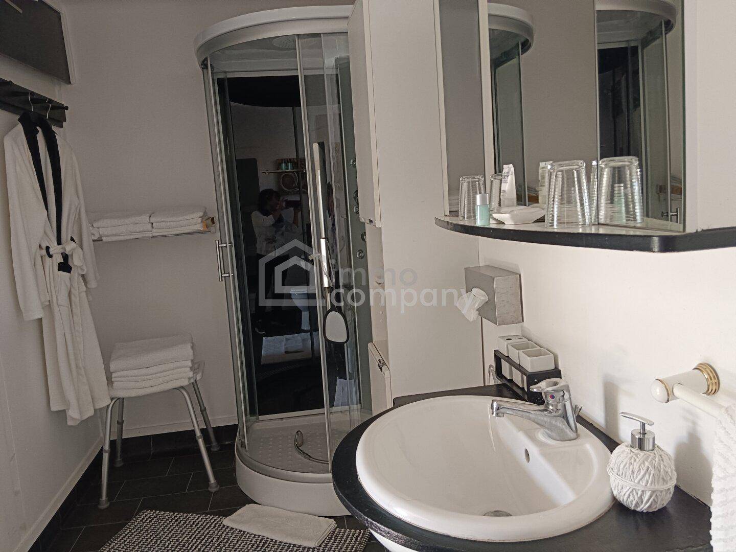 Modernes Badezimmer mit runder Duschkabine, Waschbecken und Spiegelschrank.