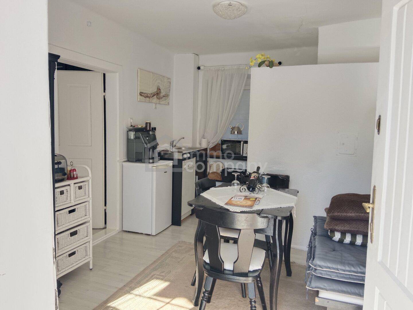 Kleine Küchenzeile mit Essbereich, Kühlschrank und Kaffeemaschine.