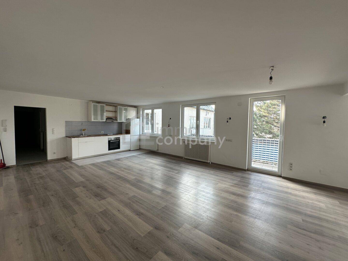 Geräumiger Wohn- und Essbereich mit moderner Küchenzeile und Zugang zum Balkon.