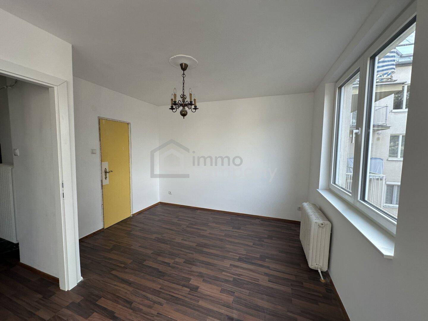 Gemütliches Zimmer mit dunklem Laminatboden und klassischem Kronleuchter.