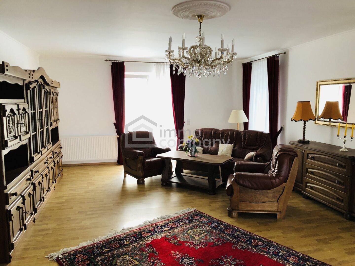 Klassisch eingerichtetes Wohnzimmer mit Ledersofas, Holzmöbeln und einem großen Kronleuchter.