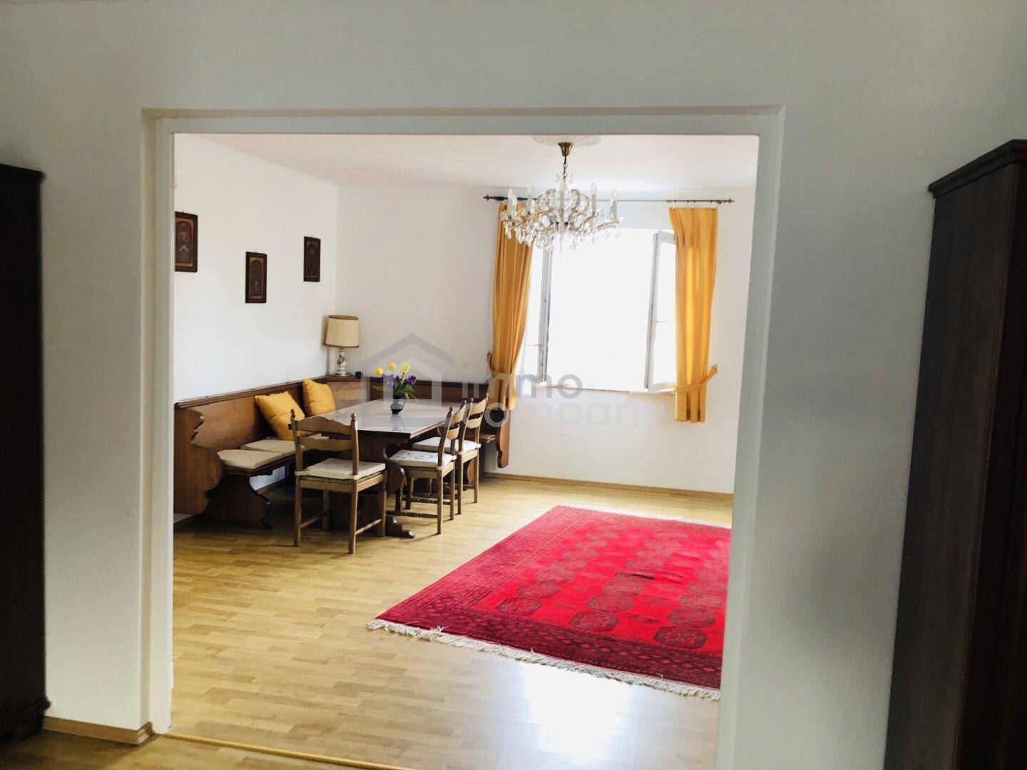 Separater Essbereich mit Holzbänken, Esstisch und einem Fenster mit gelben Vorhängen.