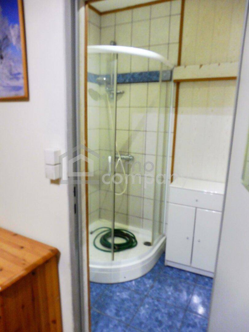 Kleines Badezimmer mit Eckduschkabine, blauen Fliesen auf dem Boden und weißen Wandfliesen.