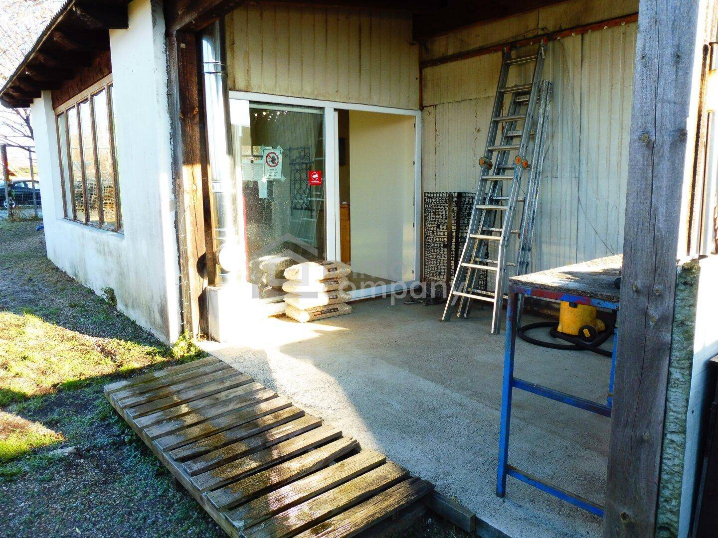 Seitlicher Eingangsbereich des Gebäudes mit einer Holzrampe für den Zugang und gelagerten Säcken im Inneren.