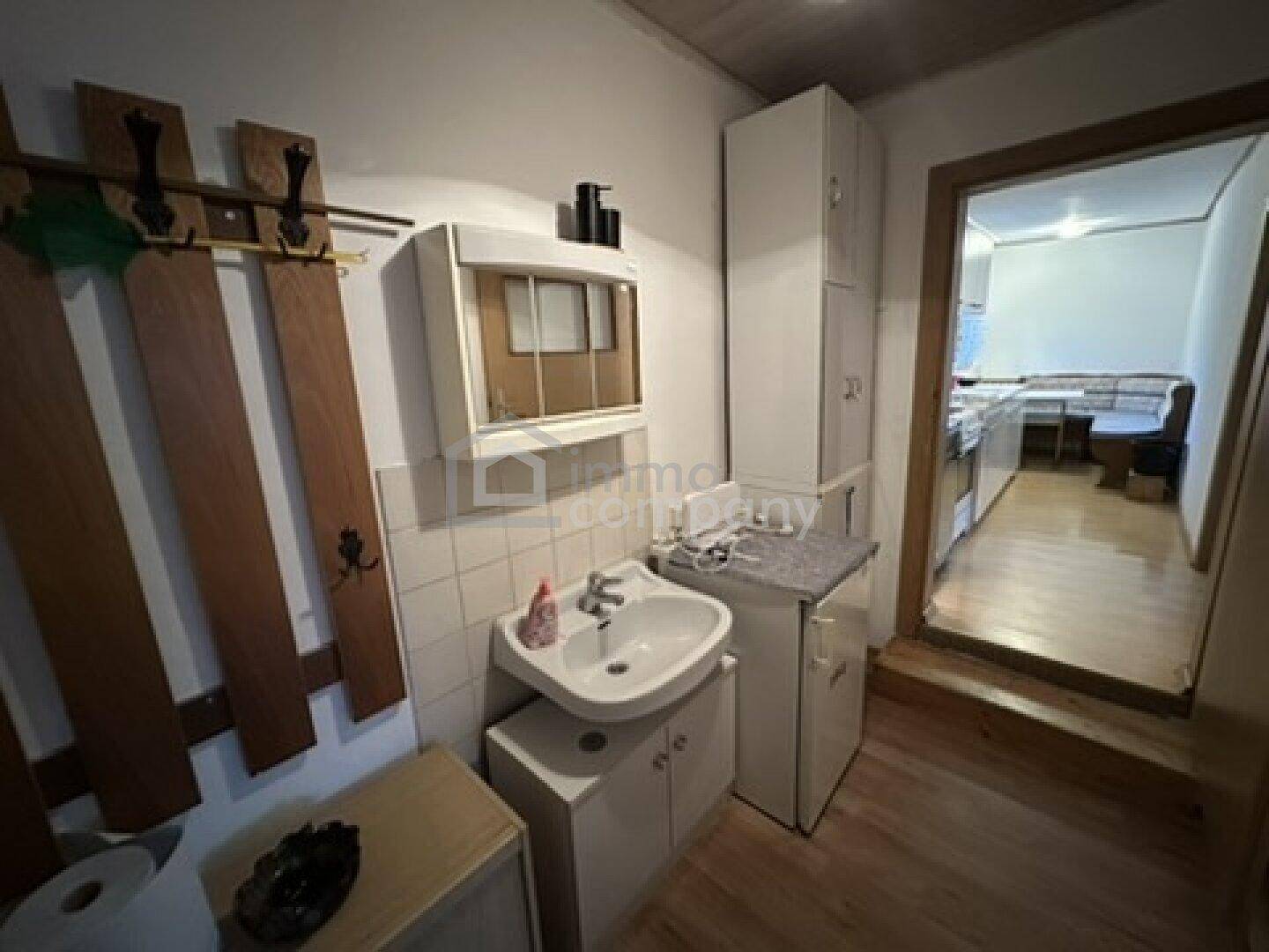 Einfaches Badezimmer mit Waschbecken und Spiegelschrank, funktional und hell gefliest.