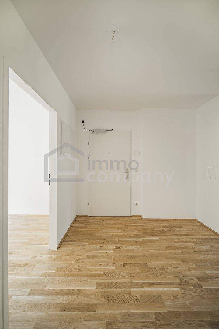 Eingangsbereich mit Holzboden und weißer Wohnungstür in einem gepflegten Zustand.