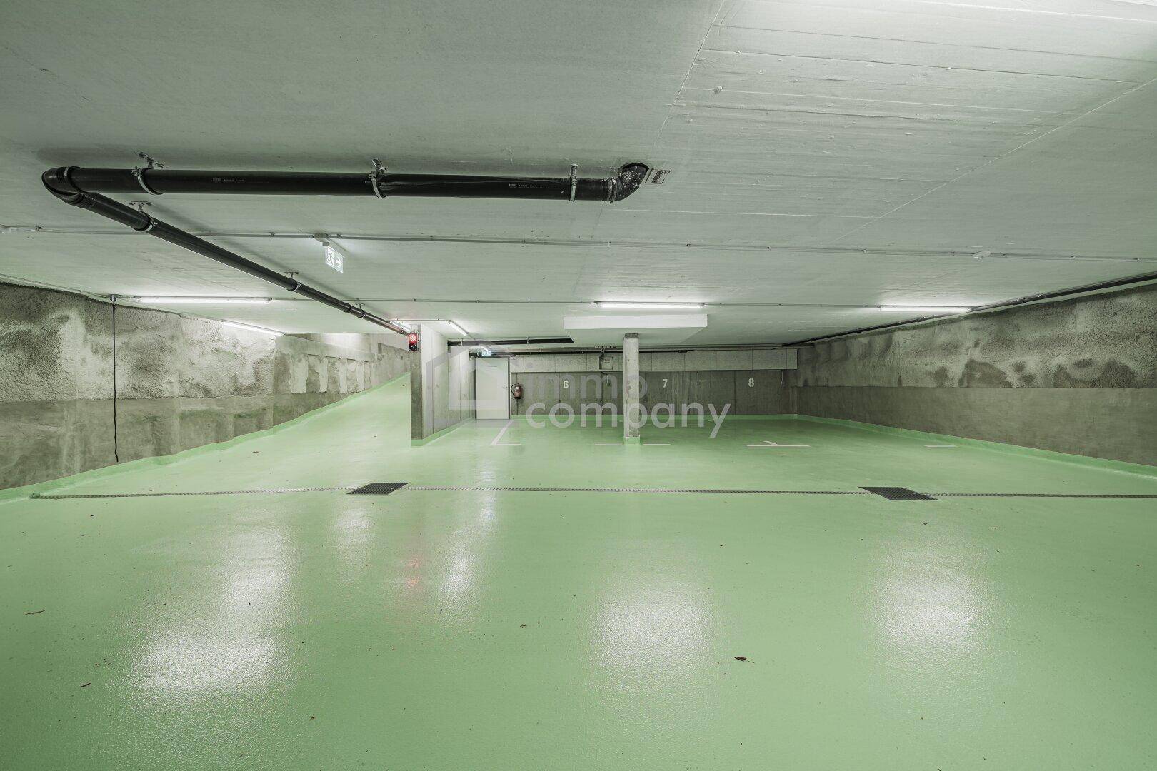 Geräumige Tiefgarage mit markierten Stellplätzen und grünem Bodenbelag.