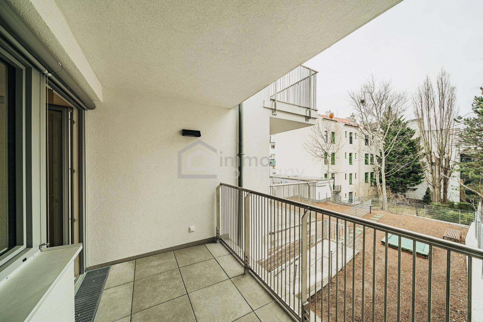 Geräumiger Balkon mit Fliesenboden, Metallgeländer und Blick ins Grüne.