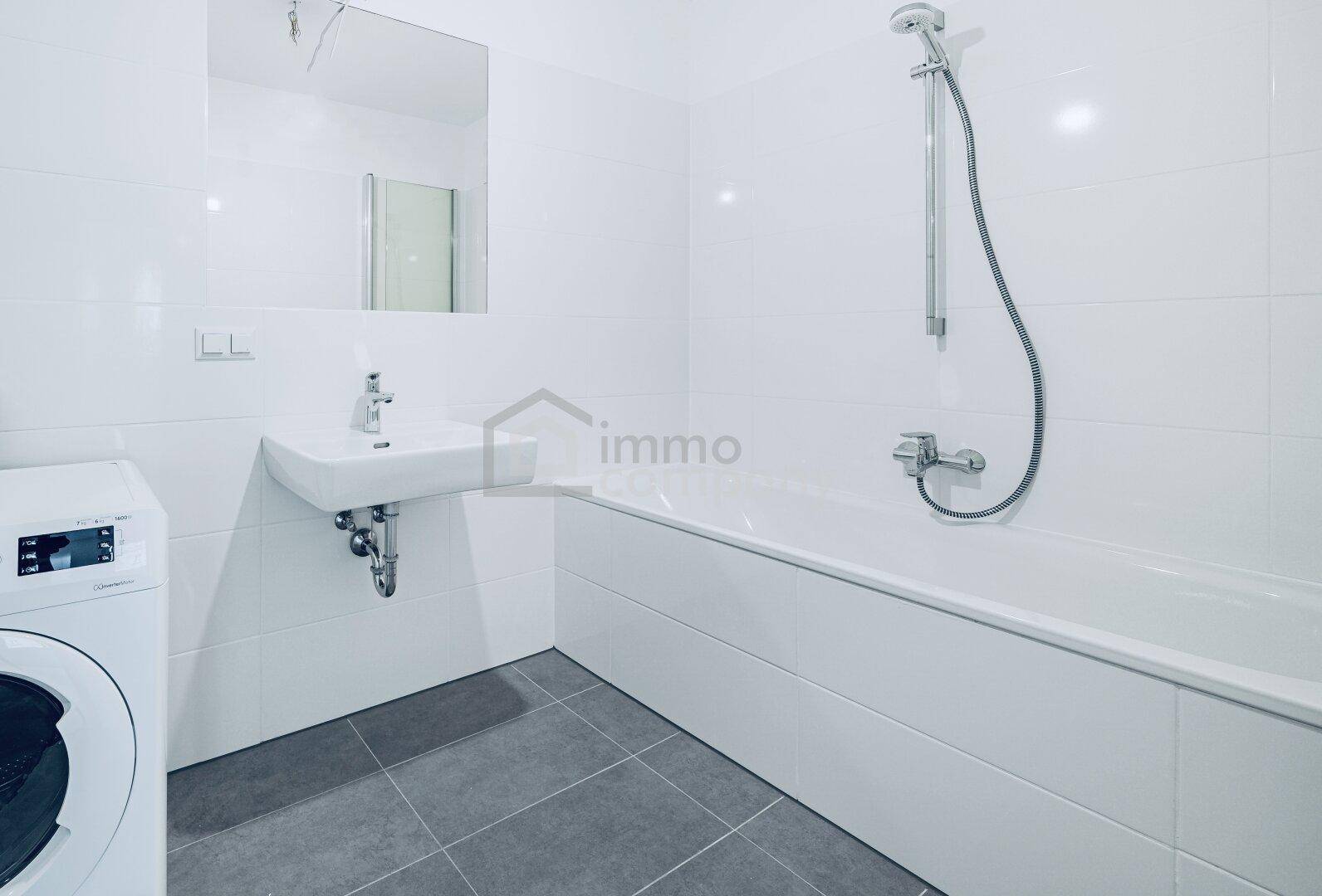 Modernes Badezimmer mit Badewanne, Waschbecken und integrierter Waschmaschine.
