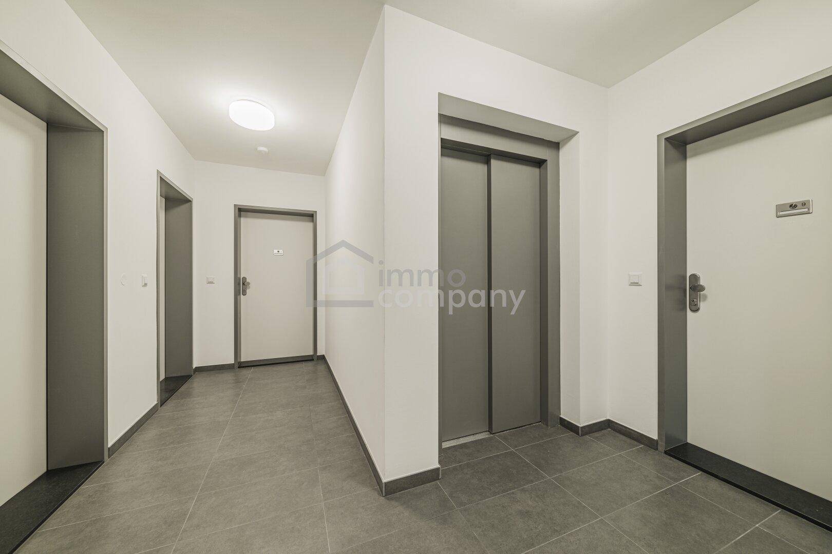 Heller Hausflur mit Aufzug und Zugang zu den einzelnen Wohneinheiten.