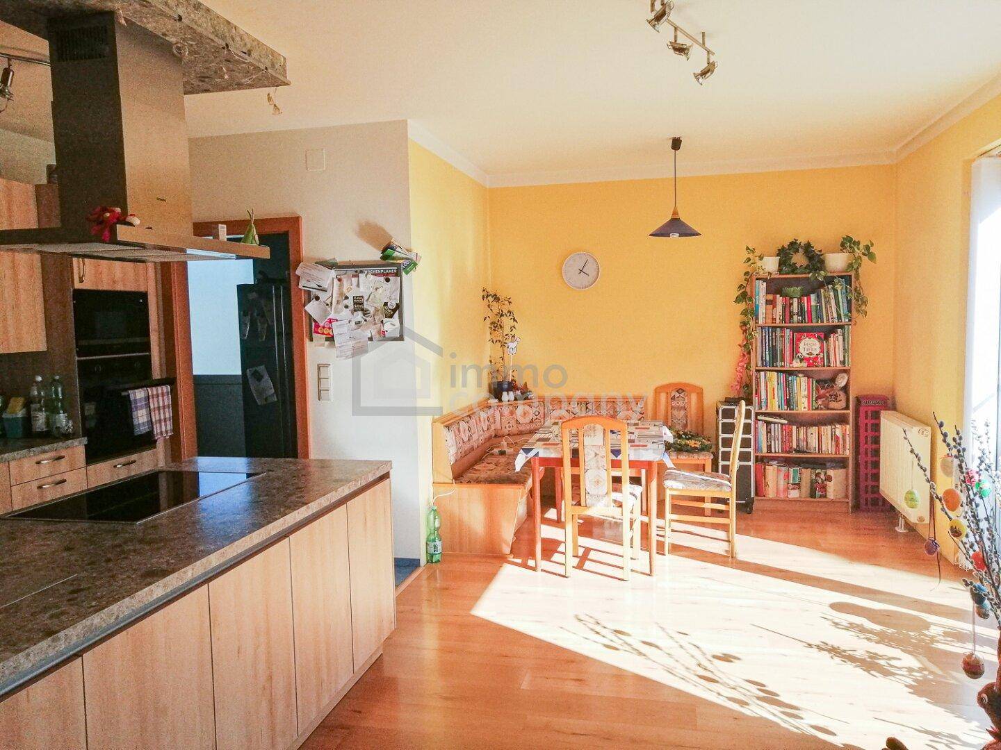 Sonniger offener Wohn-Essbereich mit Holzboden, gelben Wänden und integrierter Küche.