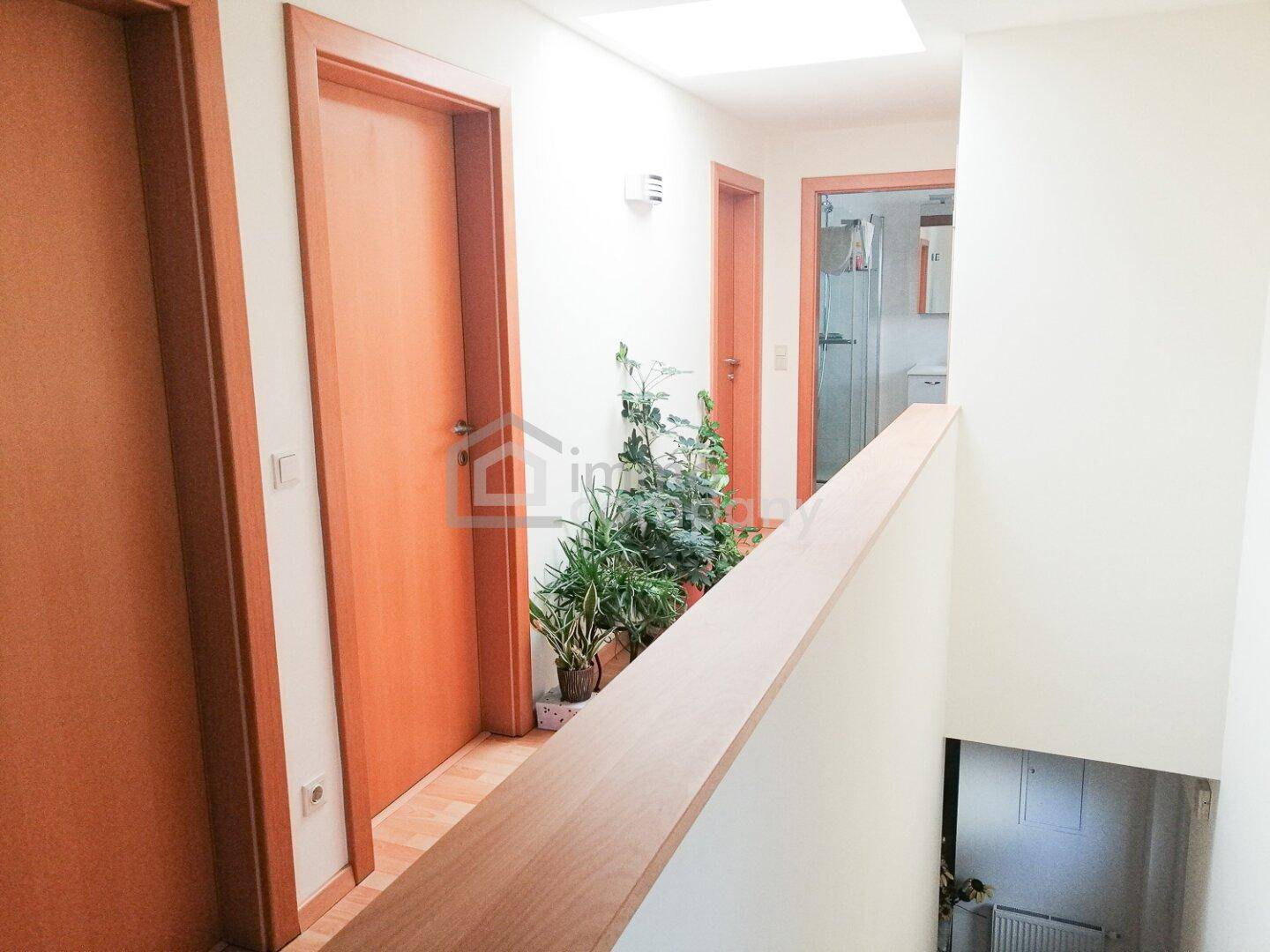 Oberer Flur mit Holzboden, mehreren Türen und Pflanzen als Dekoration.