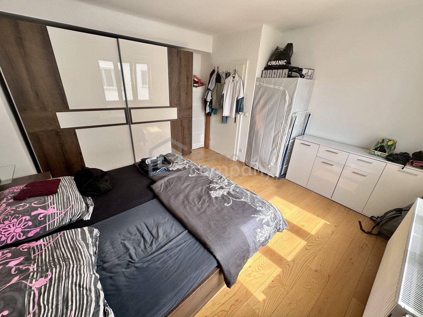 Schlafzimmer mit Holzboden, großem Kleiderschrank und viel Tageslicht.