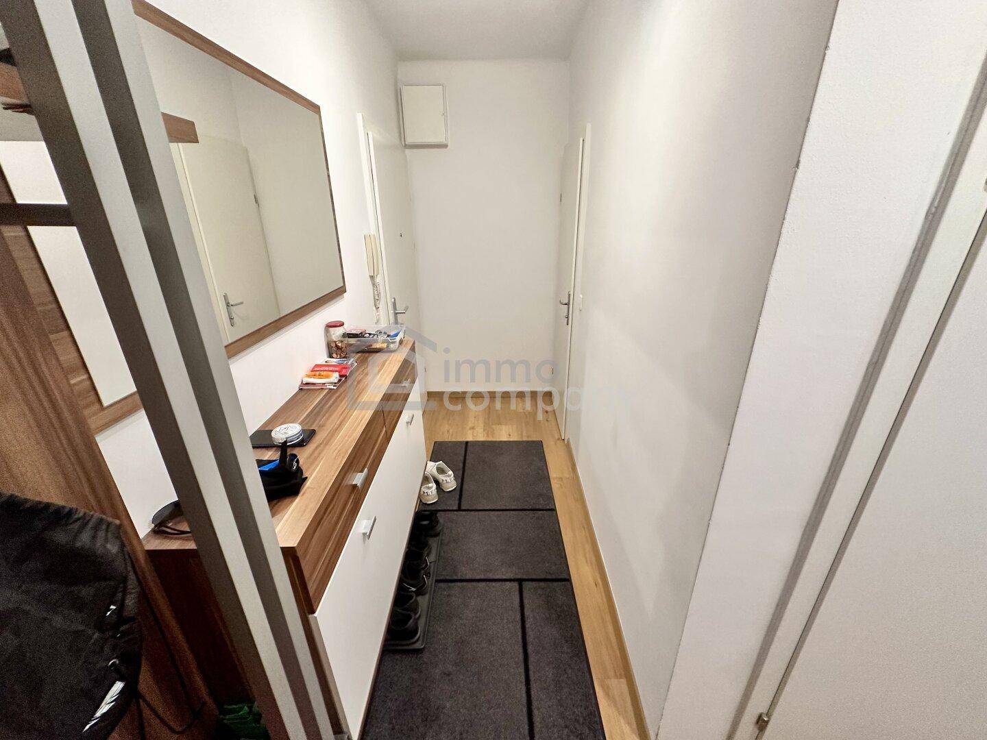 Eingangsbereich mit Garderobe, Spiegel und einer Kombination aus Fliesen- und Holzboden.