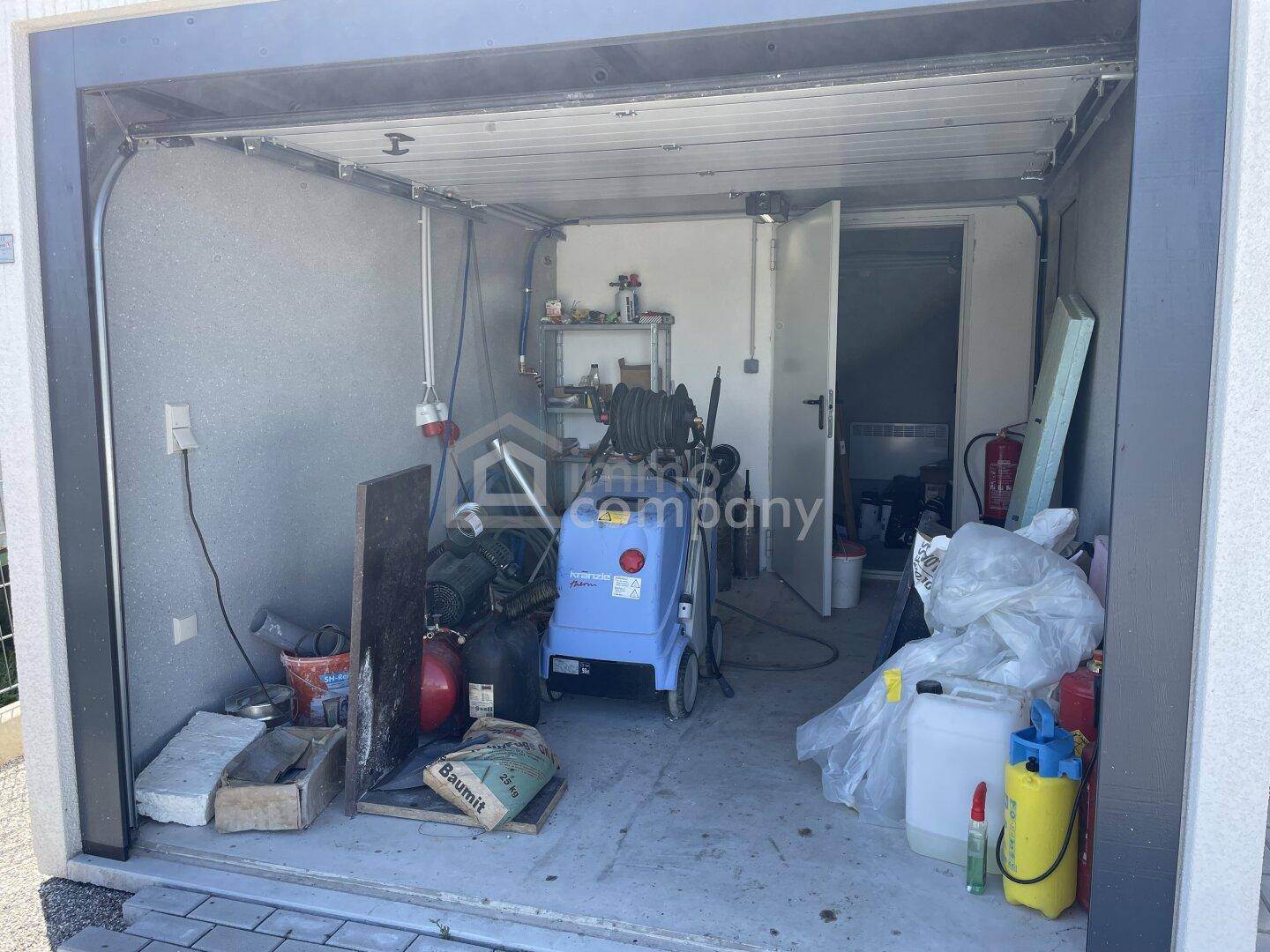 Innenansicht einer Garage oder eines Lagerraums mit verschiedenen Werkzeugen und Reinigungsgeräten.