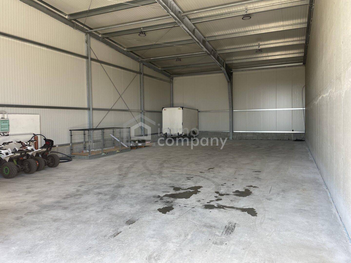 Geräumige, leere Lagerhalle mit hohen Decken, Metallkonstruktion und Betonboden, ideal für industrielle Nutzung.