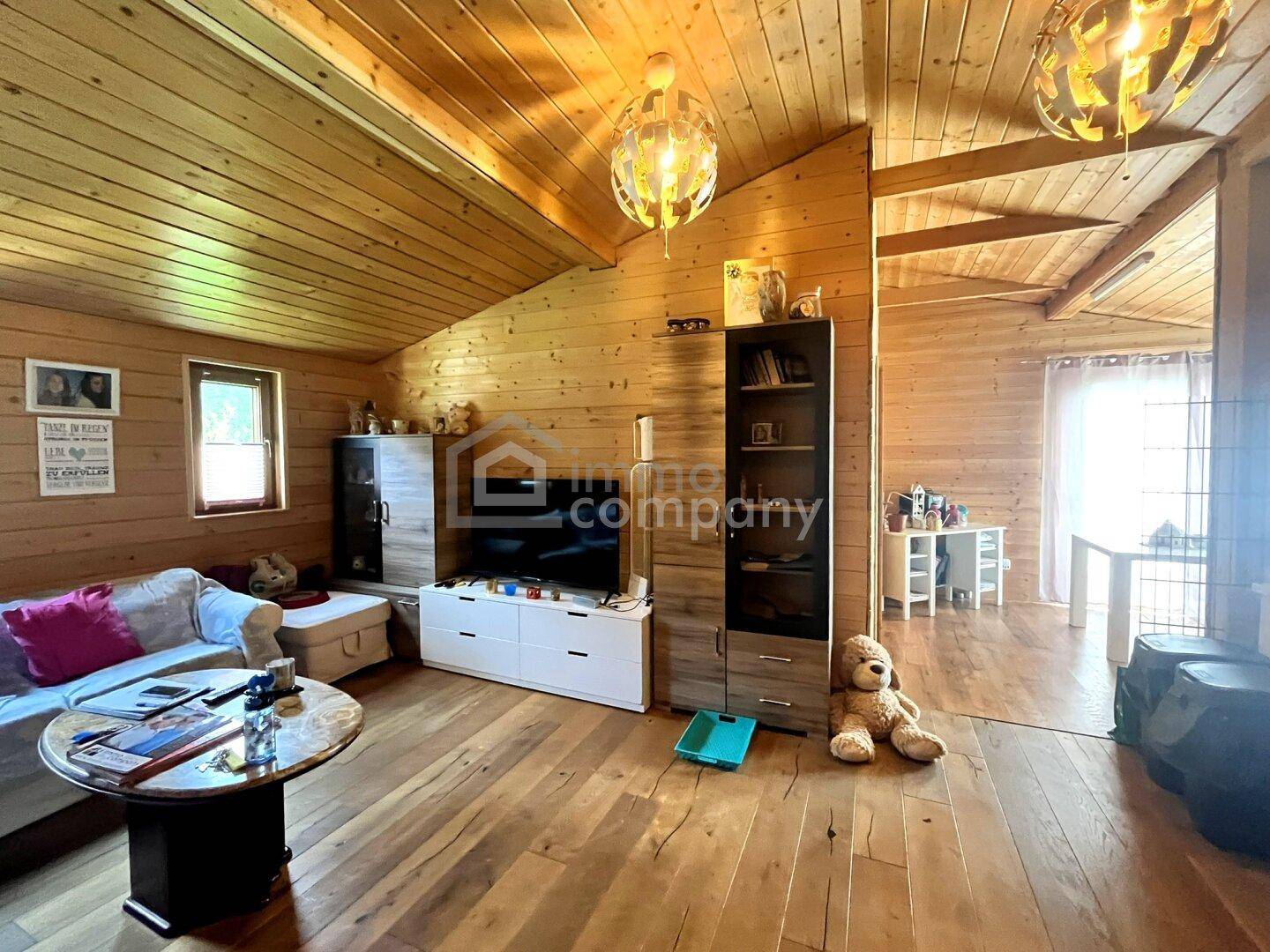 Gemütliches Wohnzimmer mit Holzböden und -wänden, ausgestattet mit Sofa und TV-Möbeln.