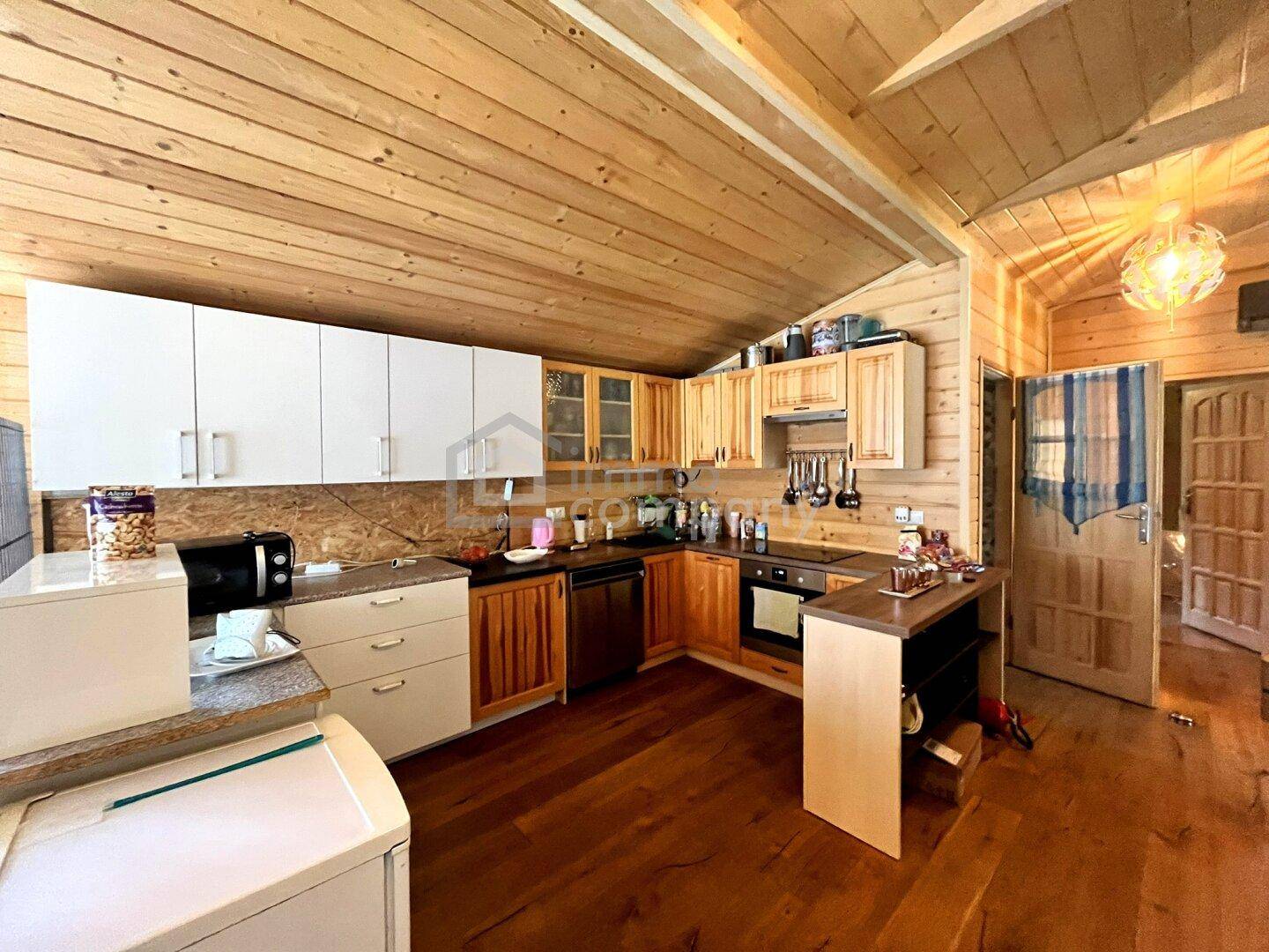 Funktionale Küche mit Holzwänden, Holzboden und einer Kombination aus weißen und hölzernen Schränken.
