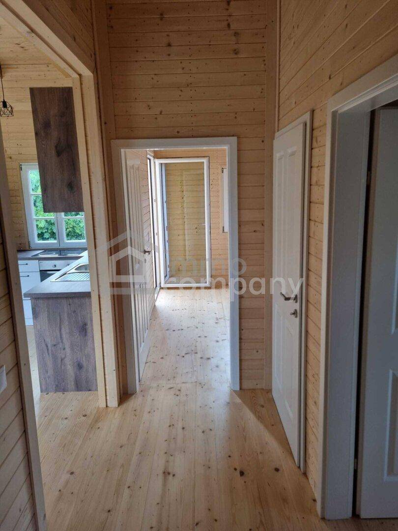 Heller Flur mit Holzwänden und Holzboden, der zu weiteren Räumen im Haus führt.