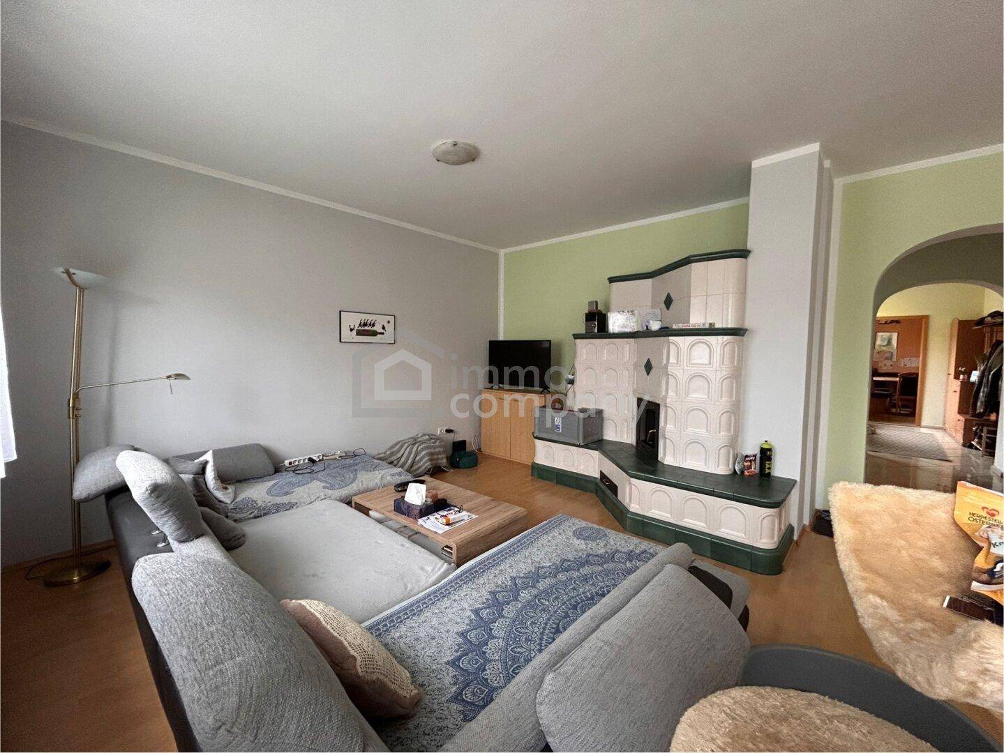 Gemütliches Wohnzimmer mit großem Sofa und einem traditionellen Kachelofen als Blickfang.