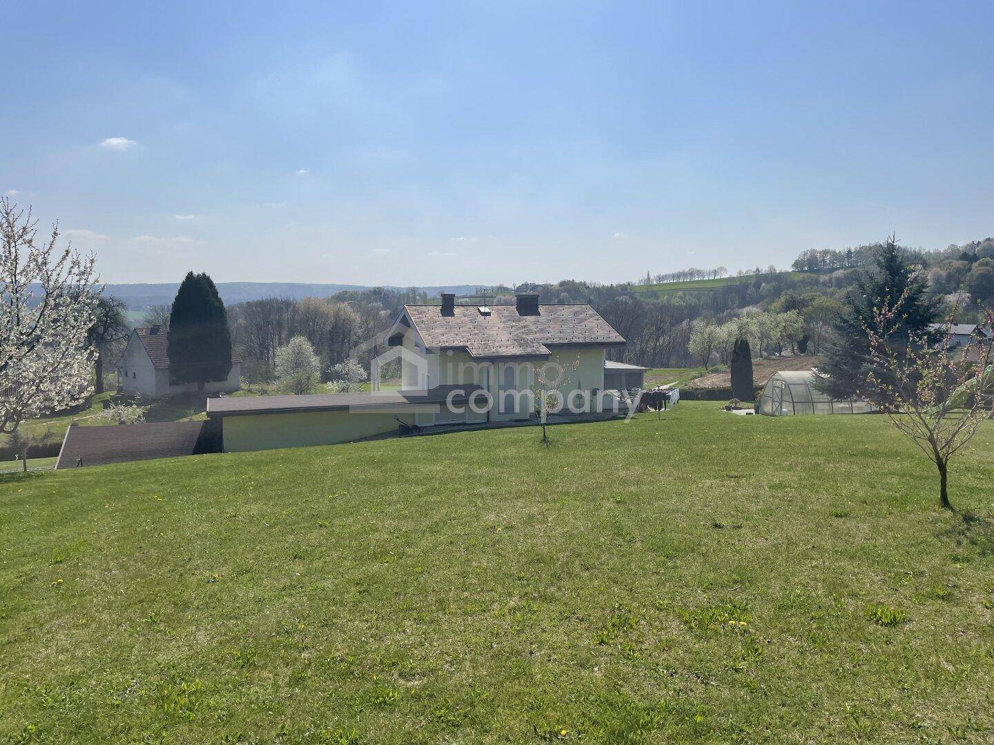Weitläufige Außenansicht des Hauses mit großem Rasen und Panoramablick auf die Landschaft.