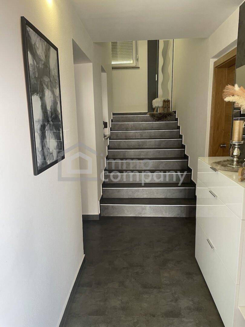 Moderner Eingangsbereich mit dunklen Treppenstufen und heller Wandgestaltung.