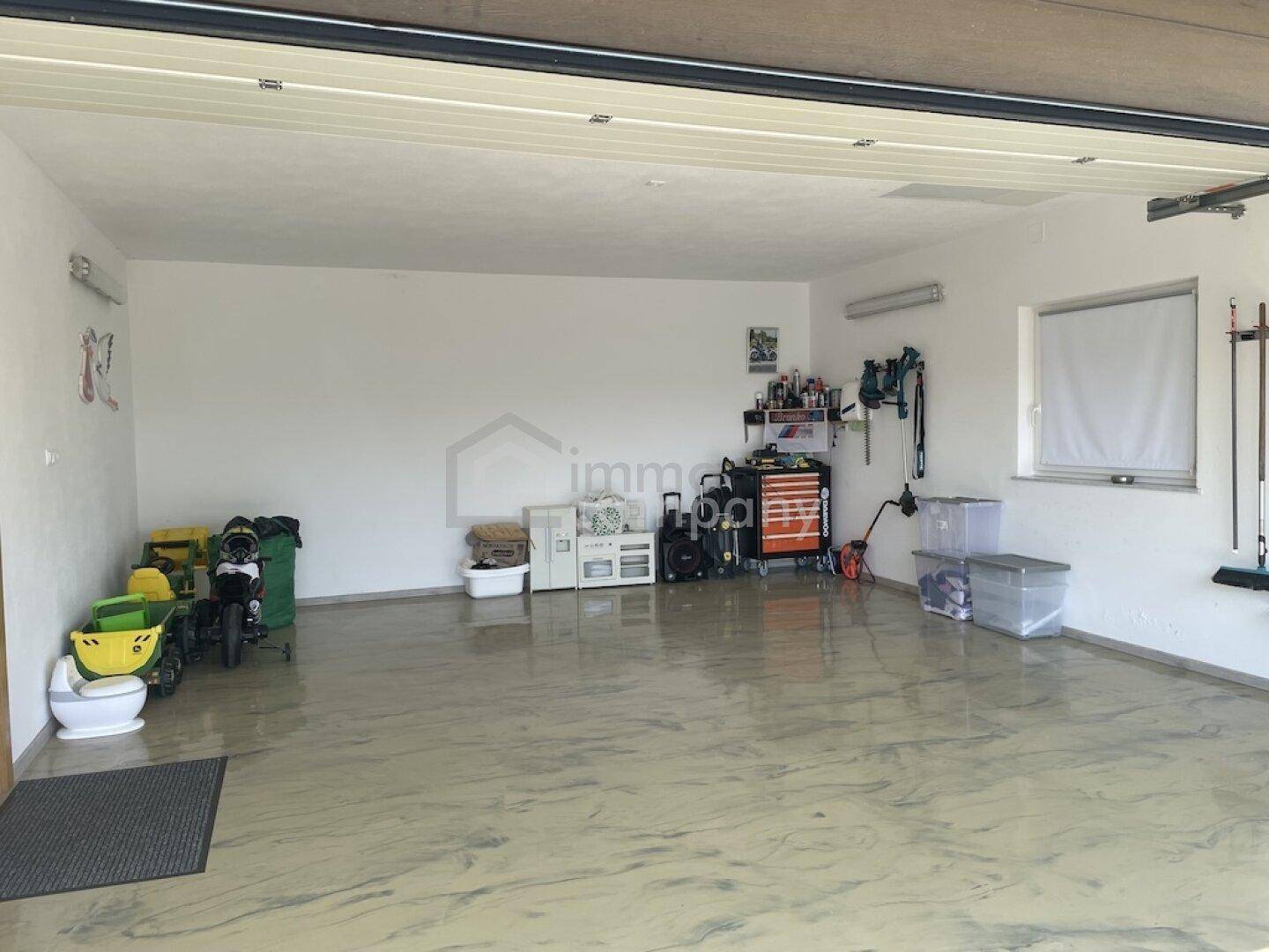 Geräumige Garage mit viel Stauraum und Werkzeugen an der Wand.