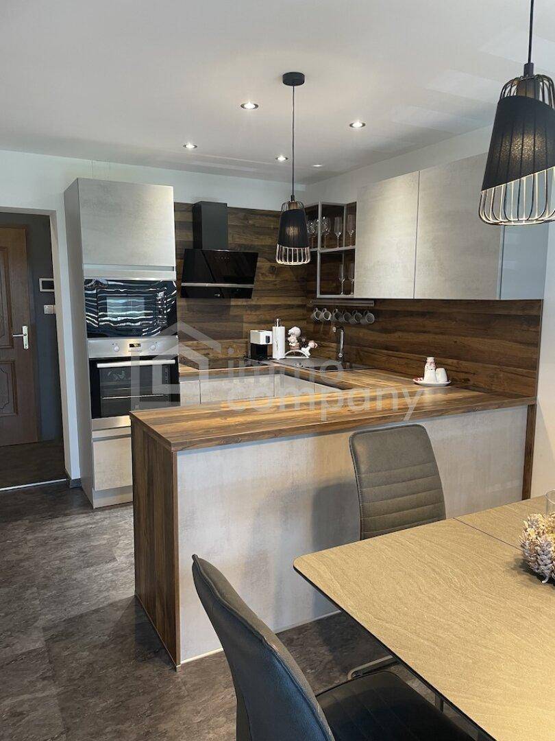 Moderne Einbauküche mit Holz- und Betonelementen, integriertem Essbereich.
