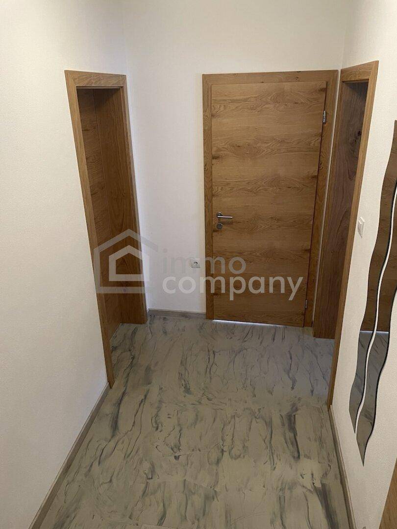 Heller Flur mit modernen Holztüren und gefliestem Boden.