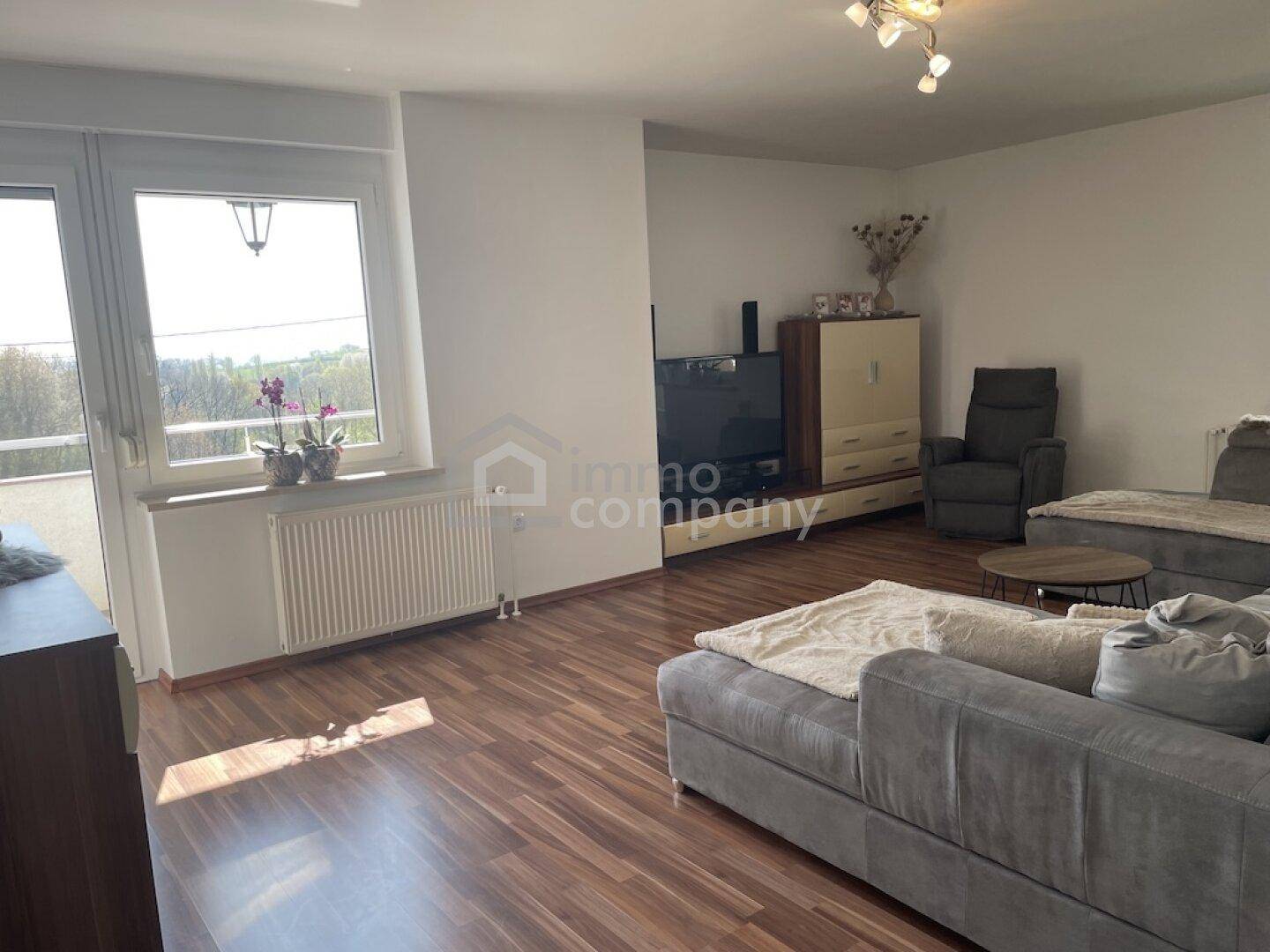 Geräumiges Wohnzimmer mit großem Sofa und Zugang zu einem Außenbereich.