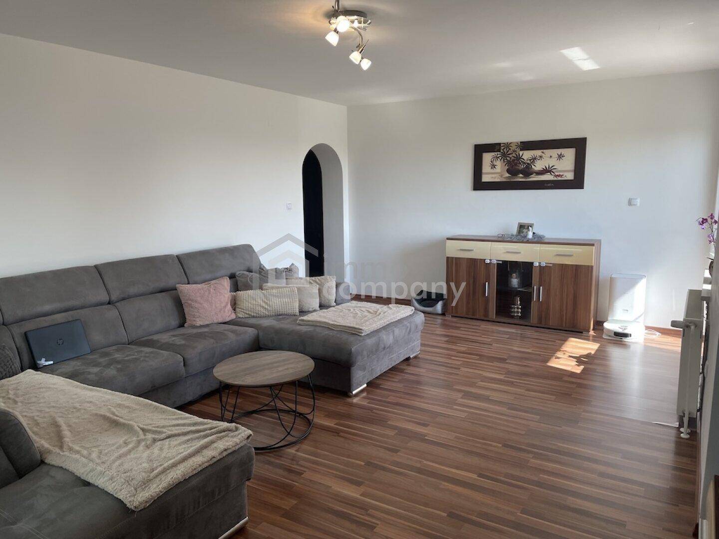 Komfortables Wohnzimmer mit großem Ecksofa und hellem Laminatboden.