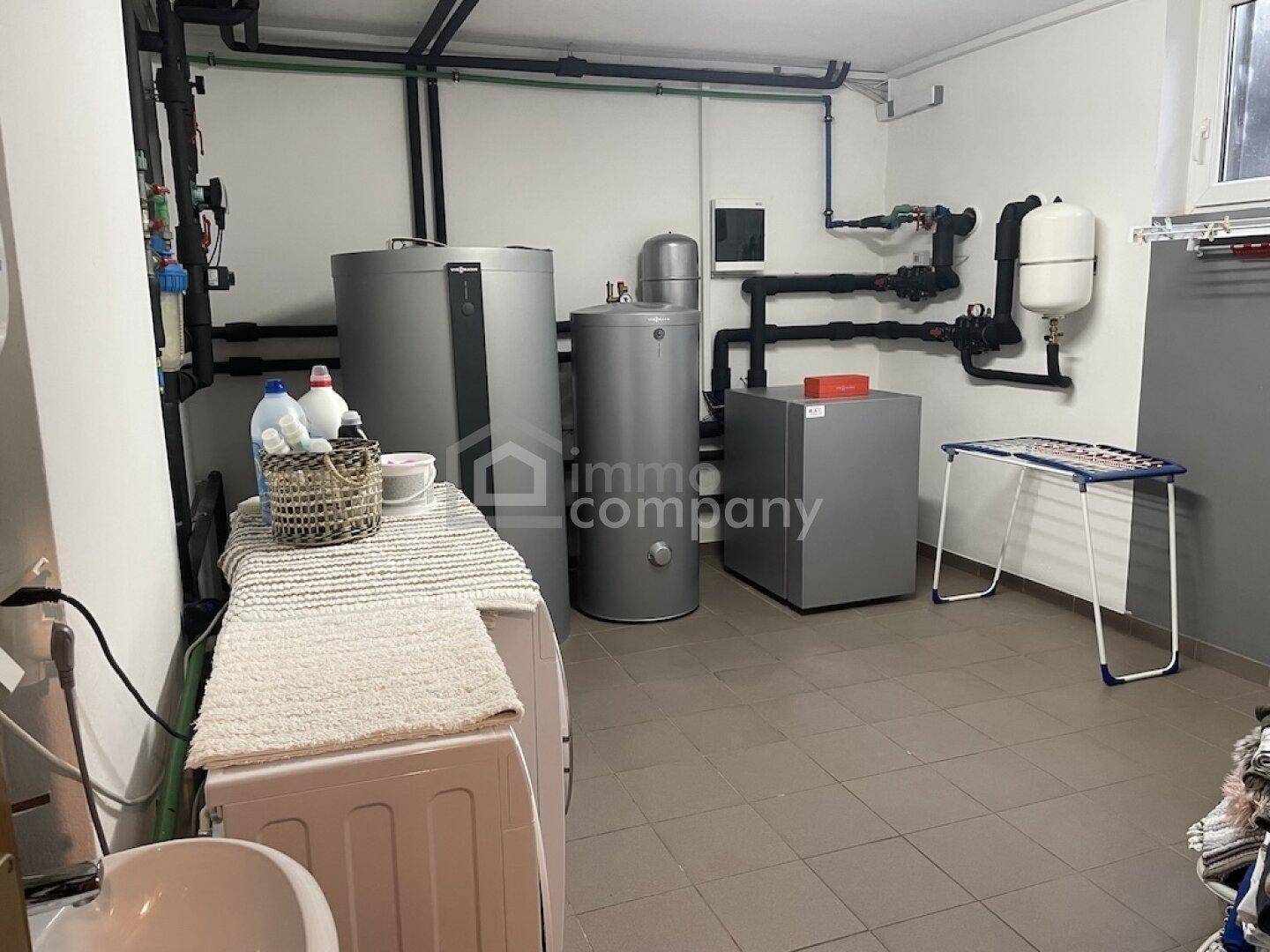 Technikraum mit Heizungsanlagen, Warmwasserspeichern und Waschmaschine.