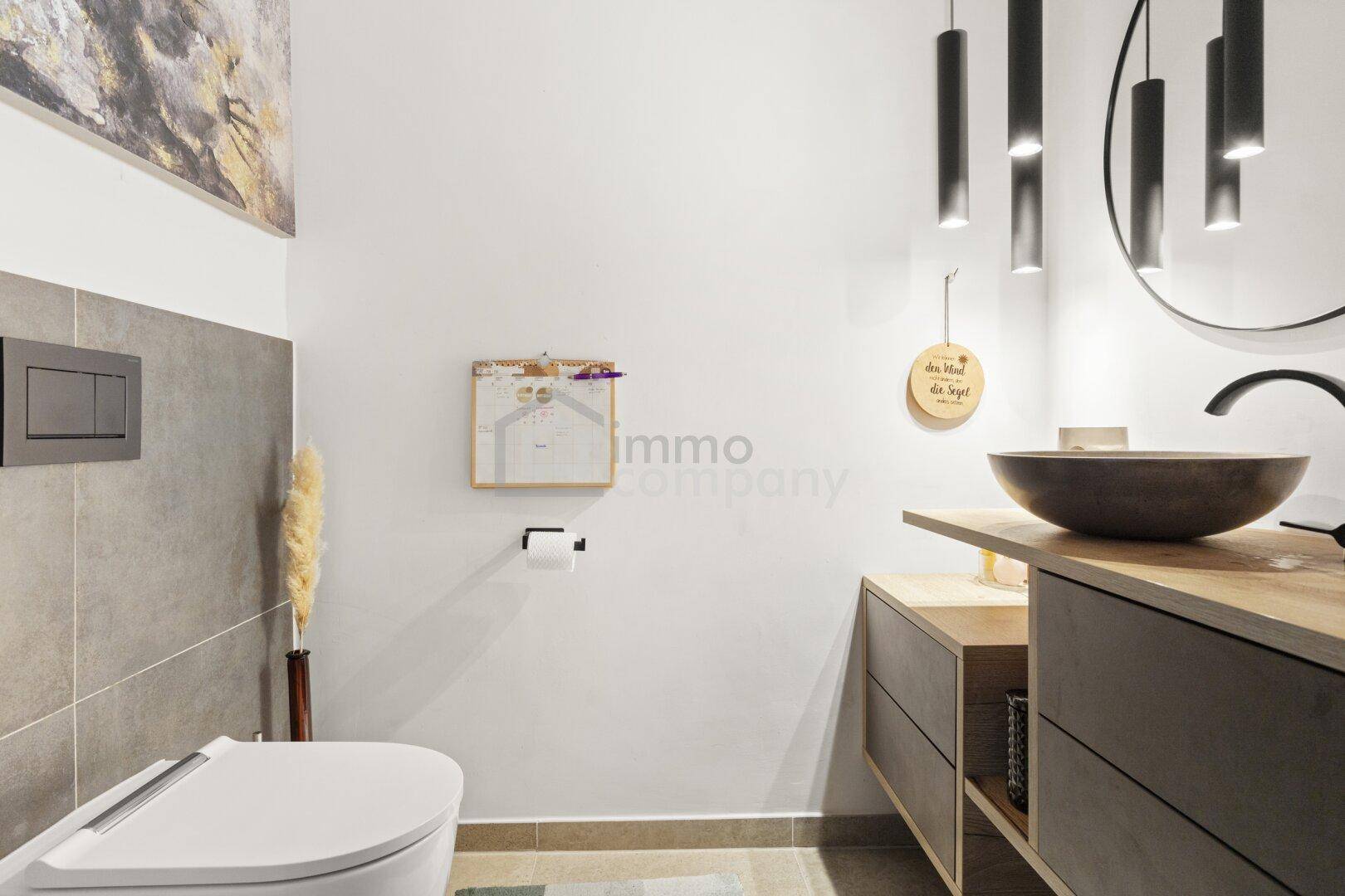 Modernes Gäste-WC mit Wand-WC, stilvollem Waschbecken und indirekter Beleuchtung.