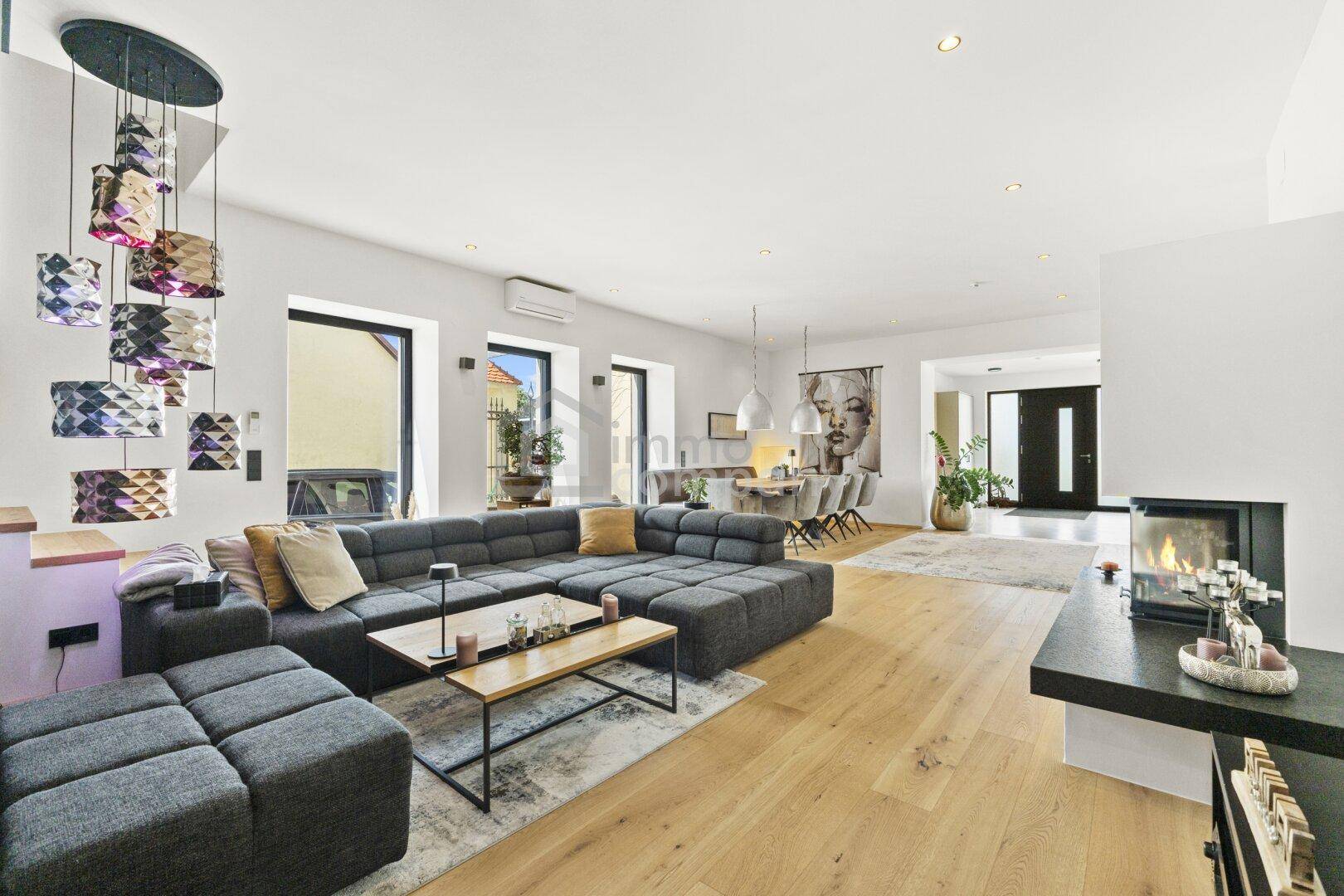 Geräumiger offener Wohn-Essbereich mit modernem Sofa, Holzboden und stilvollem Kamin.