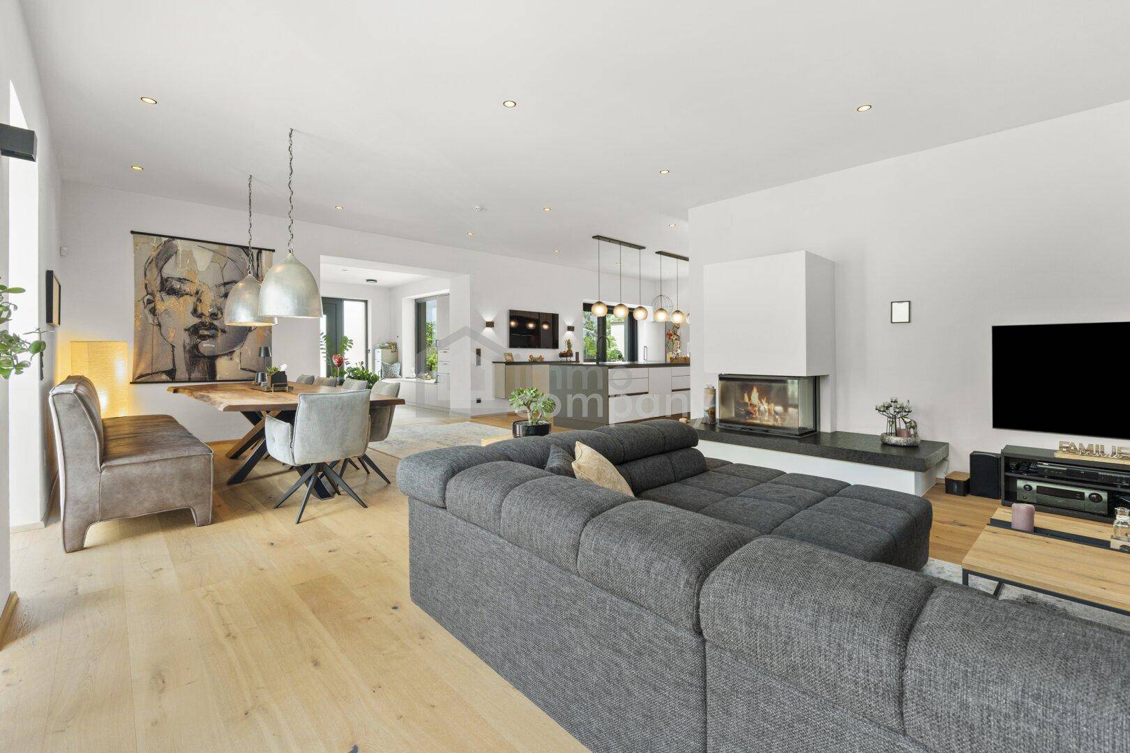Großzügiger offener Wohn-Ess-Küchenbereich mit Holzboden, modernem Sofa und Esstisch.