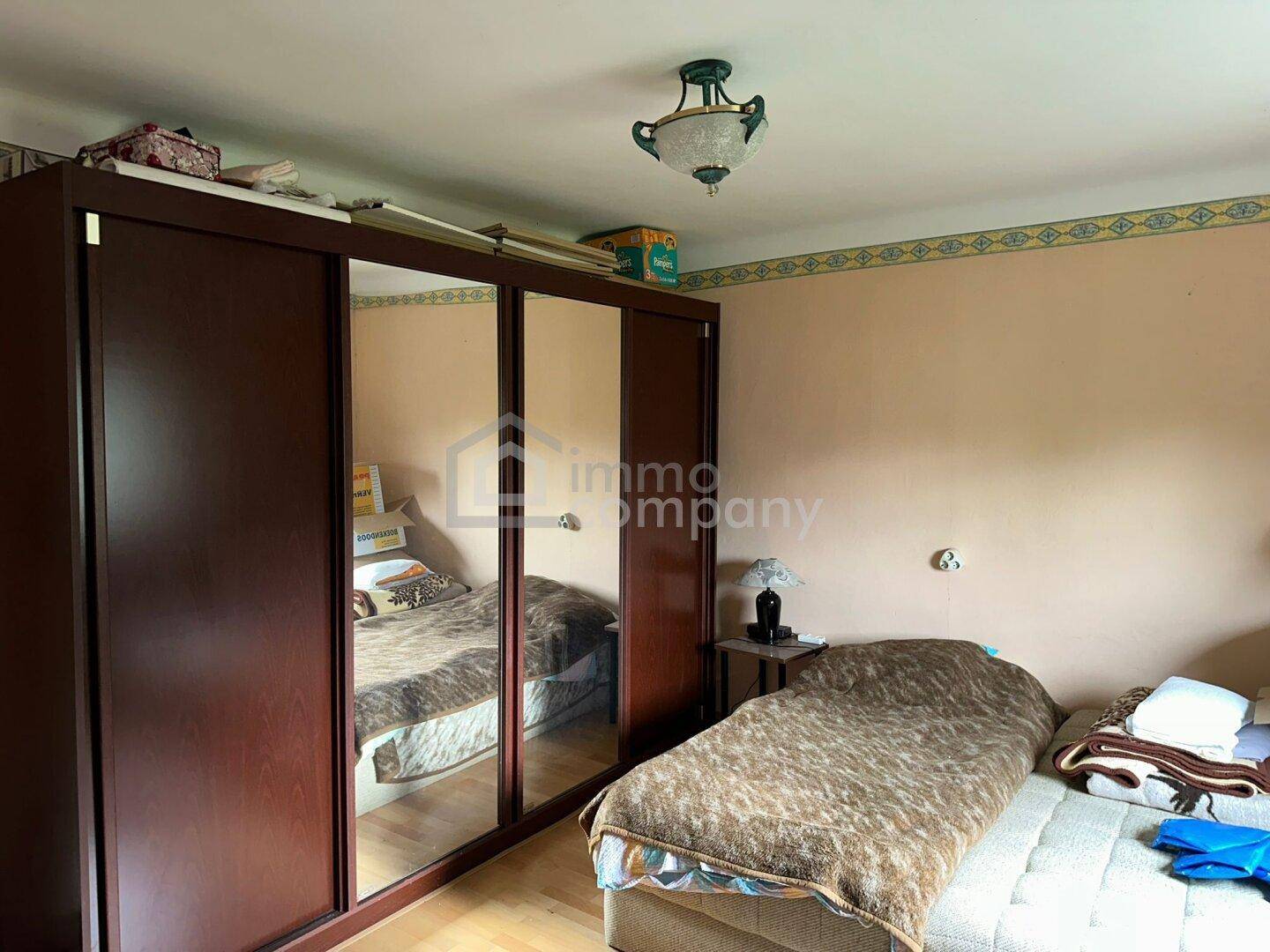 Schlafzimmer mit einem Bett und einem großen Spiegelschrank, der den Raum optisch erweitert.
