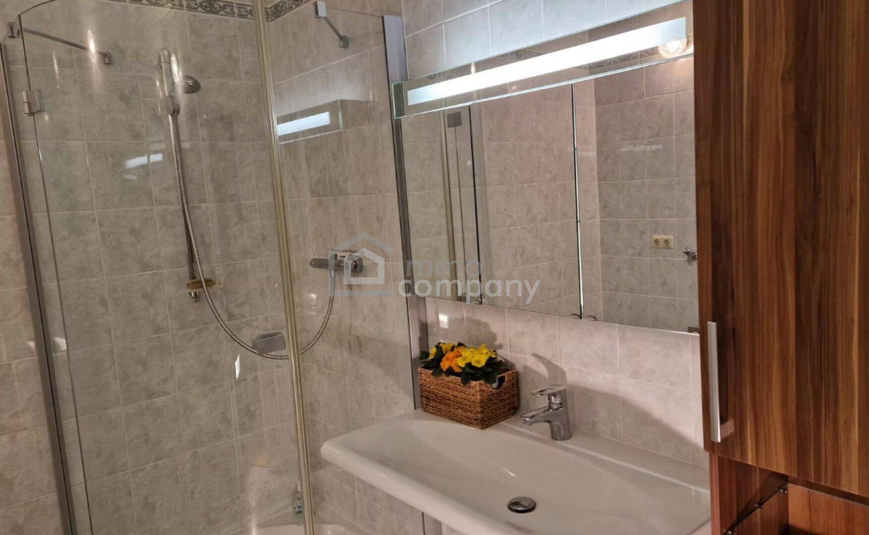 Badezimmer mit Duschkabine, Waschbecken und Spiegelschrank.